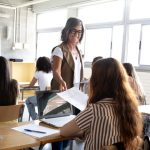 Učitelka předává studentce zadání během výuky ve třídě